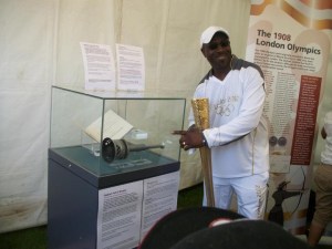 KeithYoung points to the 1948 Olympic torch while holding his own 2012 one